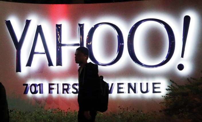 FILE - In this Nov. 5, 2014, file photo, a person walks in front of a Yahoo sign at the company's headquarters in Sunnyvale, Calif. Verizon bought Yahoo in a sale announced Monday, July 25, 2016. (AP Photo/Marcio Jose Sanchez, File)